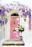 The photograph shows a gentle, romantic entranceway that could easily belong to a freshly moved-into home in North Ockendon, its calm charm unfolding in layers of pastel colour and soft light. A pale pink front door, brushed in a smooth, matte finish, stands centred against whitewashed walls that show just enough texture to suggest age and character. To one side, a shutter painted in the same blush tone completes the picture, catching light the way houses do along quieter residential streets leading towards Central Park and the countryside beyond. Arcing above the scene, wisteria cascades in tumbling sprays of lavender and lilac, the flowers hanging in loose clusters that form a dreamy floral curtain. Their imagined perfume mingles, in the mind, with the powdery sweetness of roses. At the base of the door, a compact metal bucket cradles a generous bouquet of white and cream roses, each bloom comfortably full and softly ruffled. Delicate green foliage and silvery leaves nestle between the petals, adding depth and a garden-fresh feel. A soft pink ribbon is tied around the bucket, its tails trailing just enough to draw the eye without overwhelming the arrangement. The lighting is gentle, with sunlight glancing across the step and casting faint, painterly shadows that give the doorway a sheltered, intimate feel. The overall mood is one of quiet celebration and tender optimism-the kind of doorstep floral gift you might send to congratulate someone on their new address in North Ockendon, wishing them warmth, luck, and a beautifully welcoming home.